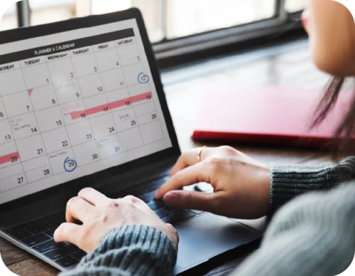 Persoan escribiendo en computador en una calendario
